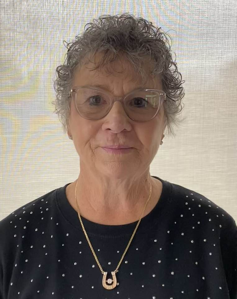 A smiling woman with curly grey hair.