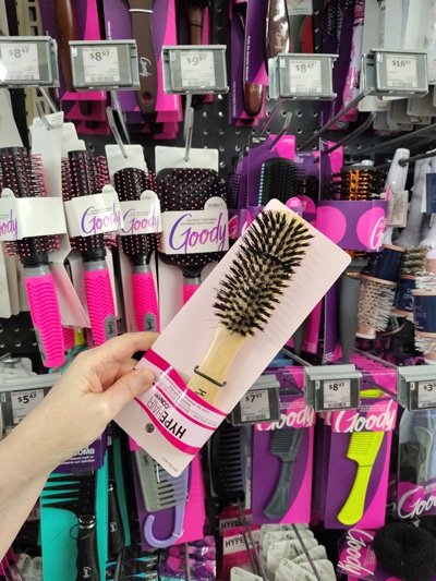 A hand holding a hair brush in a package.