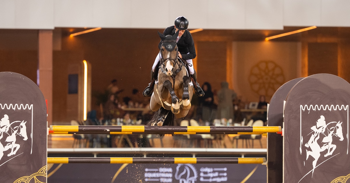 A man jumping a bay horse over a fence in Doha.