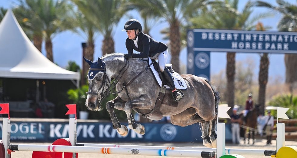 A woman jumping a grey horse over a fence in California.