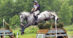 A man jumping a grey horse over a cross-country fence at Bromont.