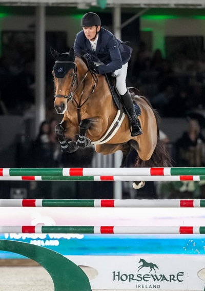 A man jumping a bay horse over a fence at WEF.