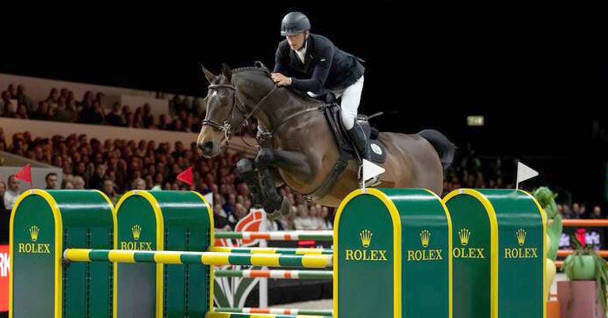 A man jumping a bay horse over a Rolex fence.