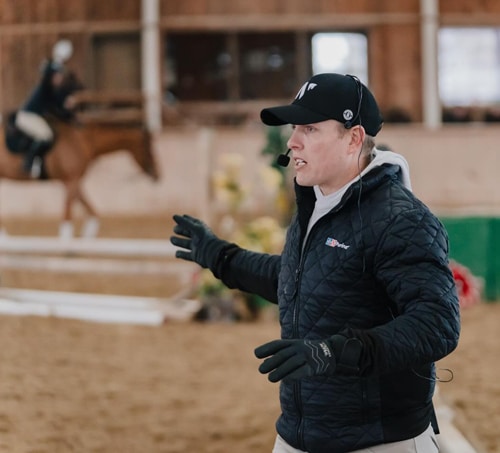 A man teaching at an indoor riding clinic.