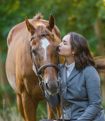 A young woman kissing her horse.