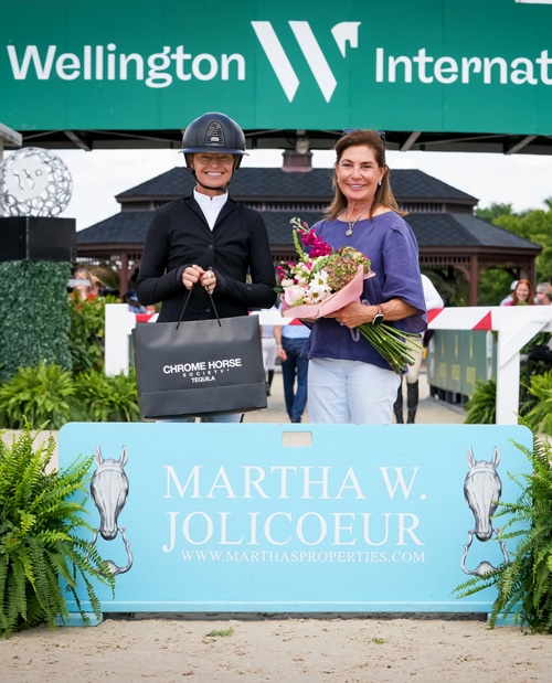 A smiling woman accepting an award from another woman.