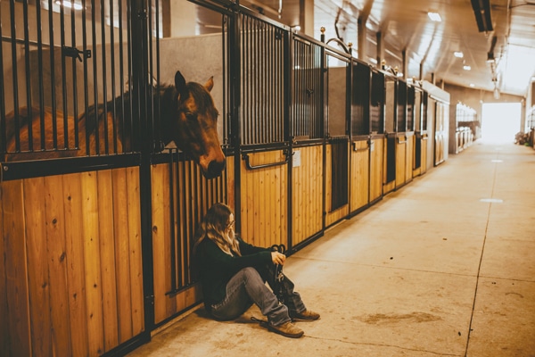 A girl sitting on the floor of a stable.