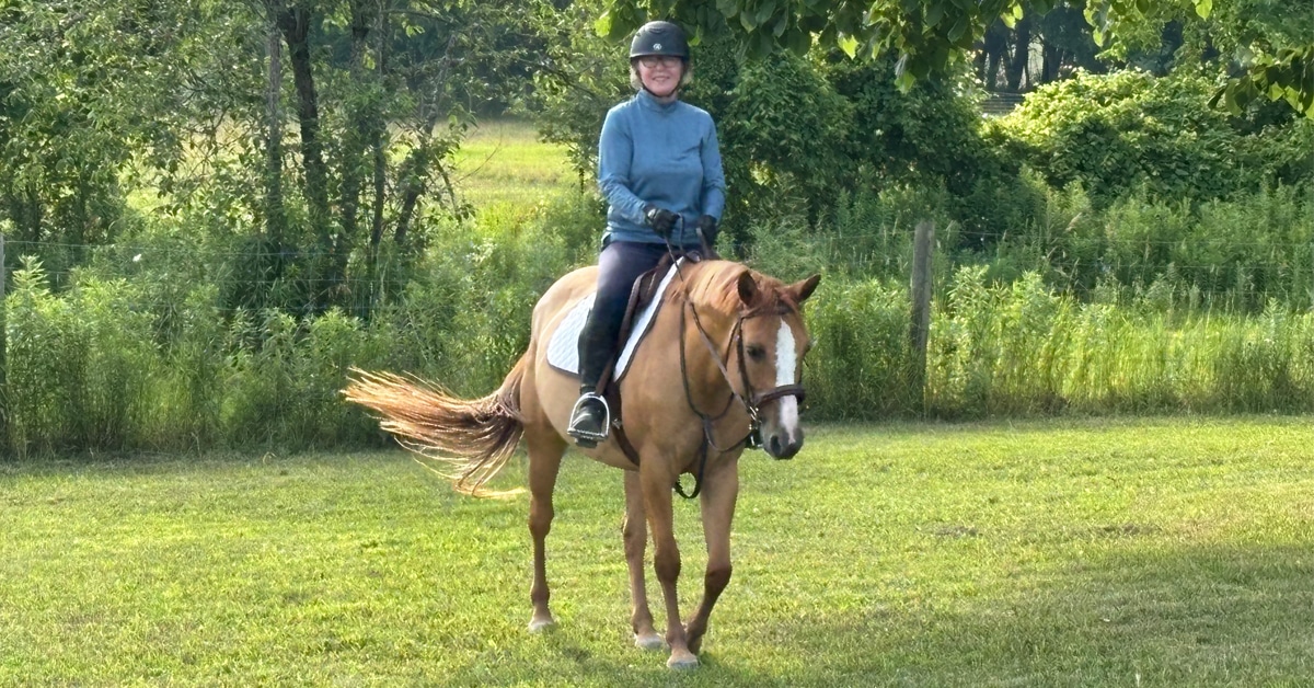 A woman riding a sorrel mare.