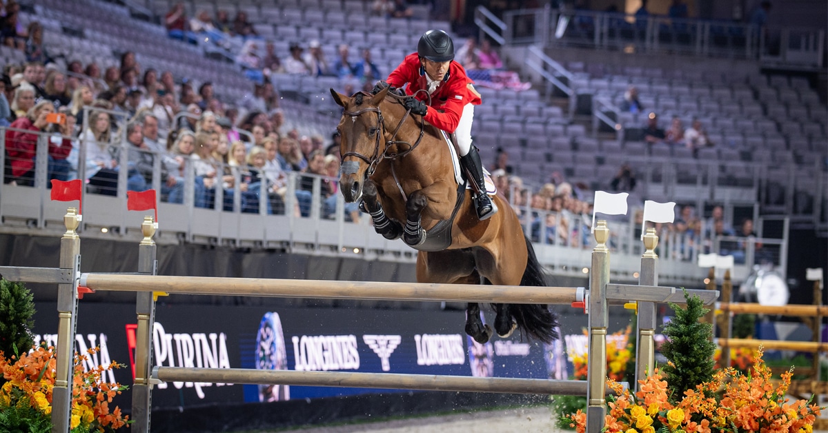 A man in a red jacket jumping a bay mare over a fence in Texas.