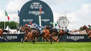 Horses racing at Longchamps in front of a Longines sign.