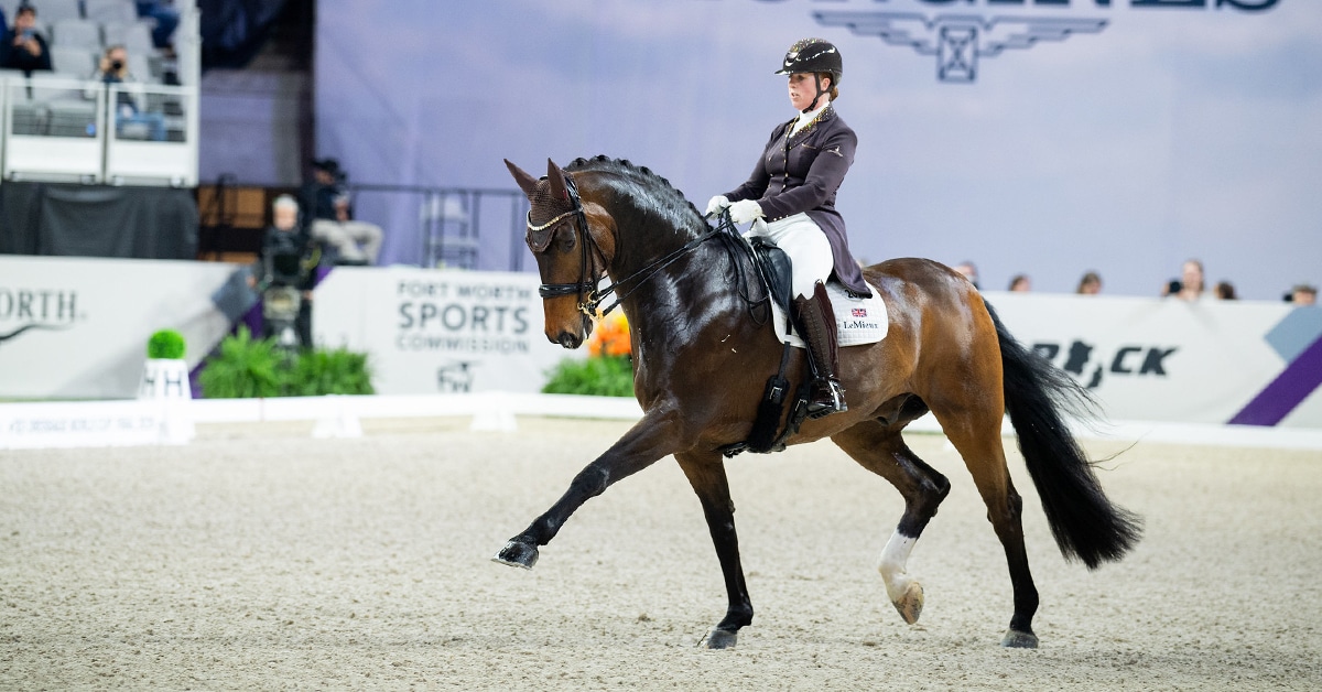 A woman riding a dark bay dressage horse during a test in an arena in Fort Worth.