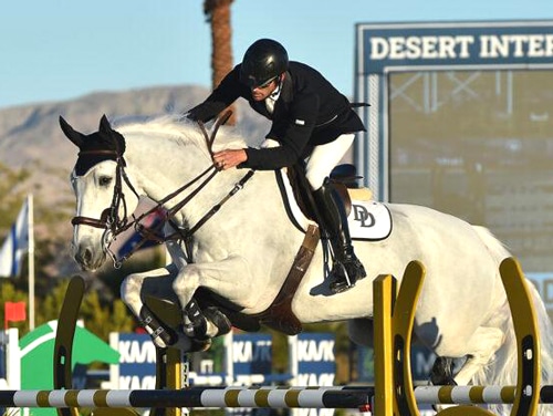 A man jumping a grey horse over a fence in California.