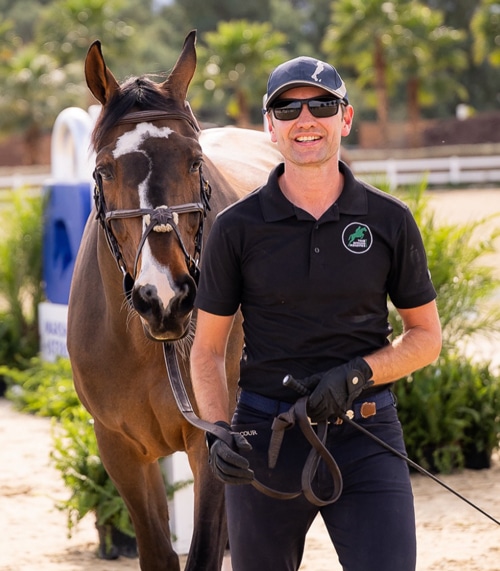 A smiling man holding a horse.