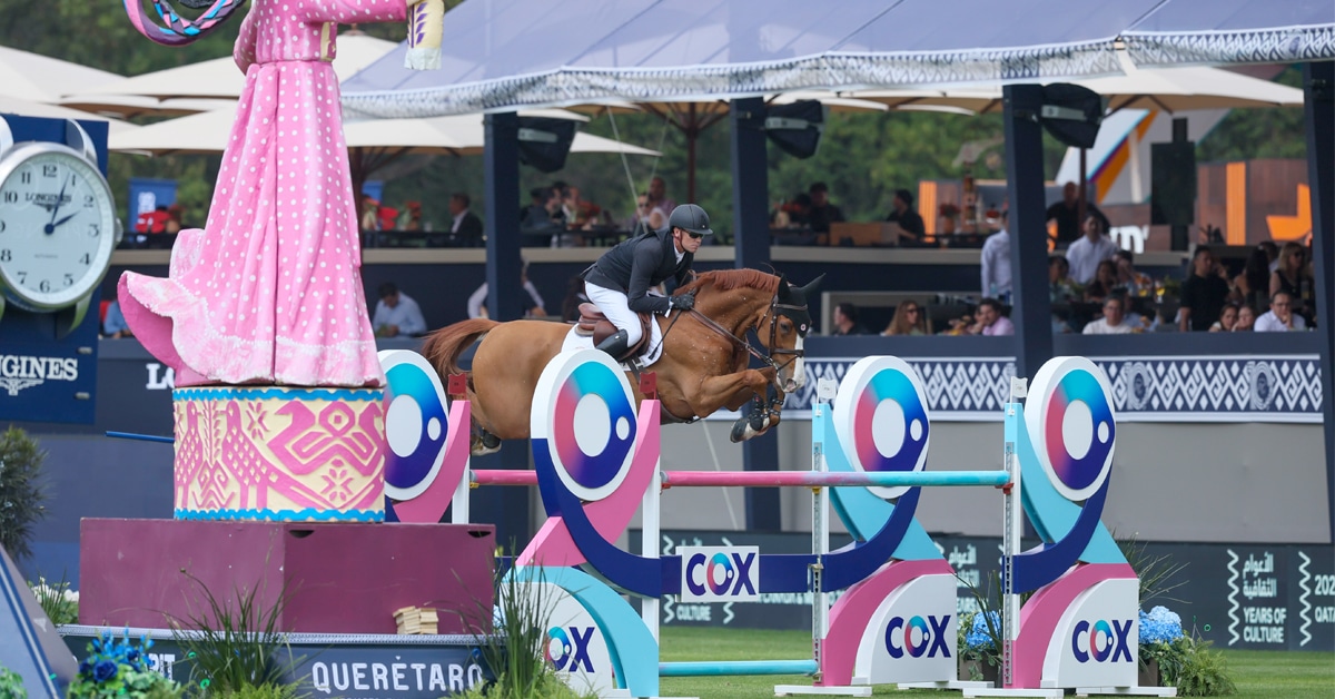 A man jumping a chestnut horse over a colourful fence in Mexico City.