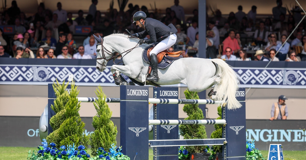 A man jumping a grey horse over a fence in Mexico.