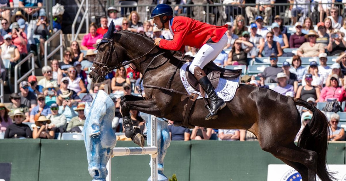 A man in a red jacket jumping a horse over a fence in Kentucky.