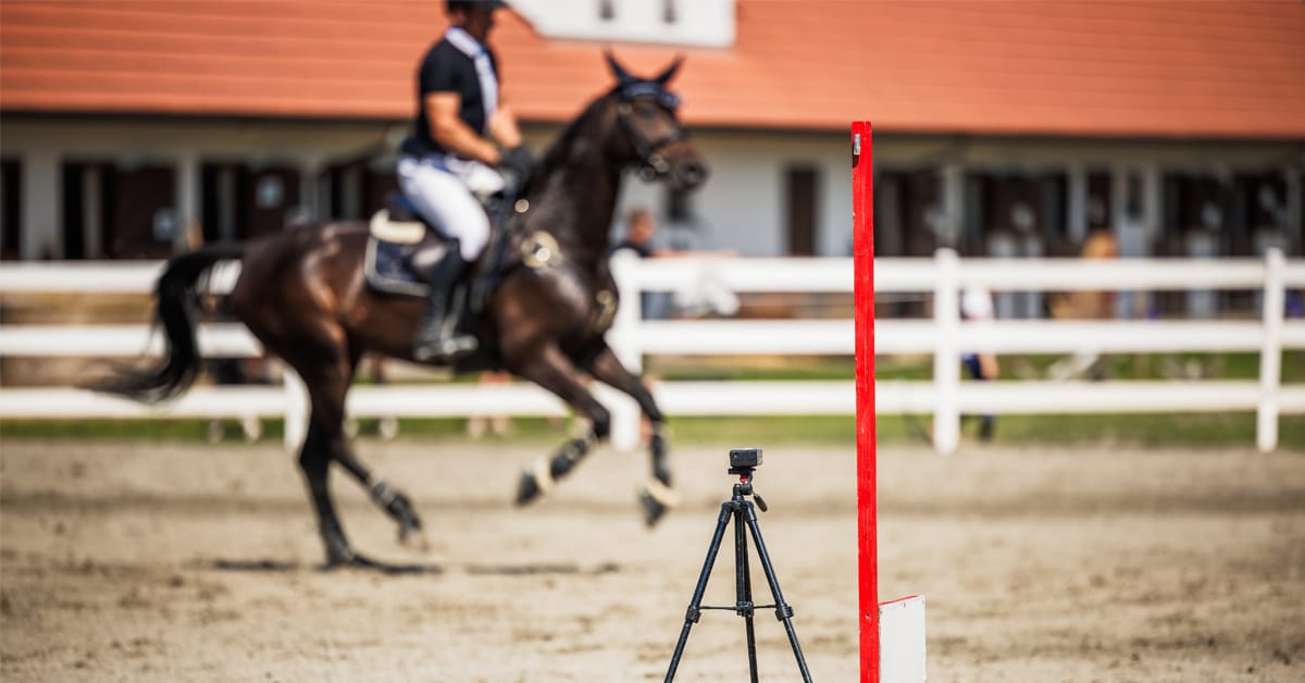A horse and rider galloping past start timers at a show.