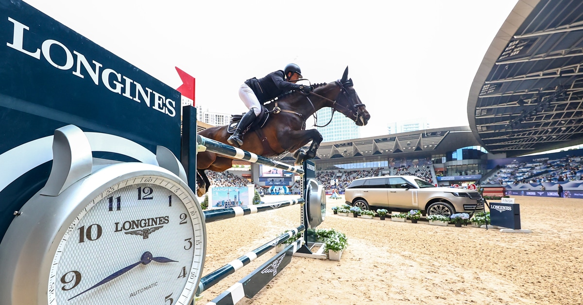 A man jumping a Longines signature fence on a bay horse.