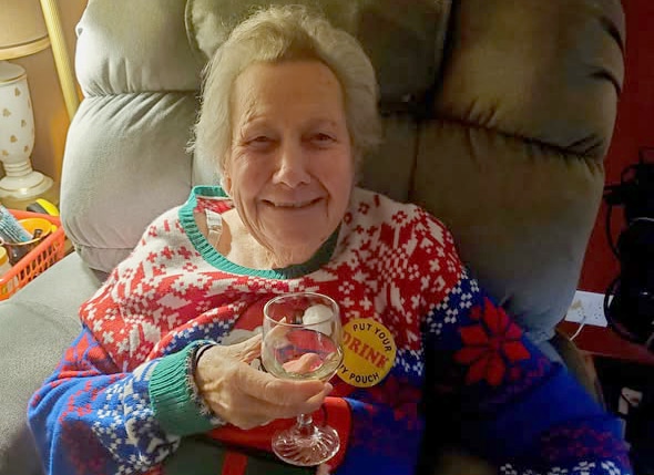 A smiling older lady with a glass of wine.