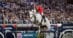 A man jumping a grey horse over a fence in a competition.