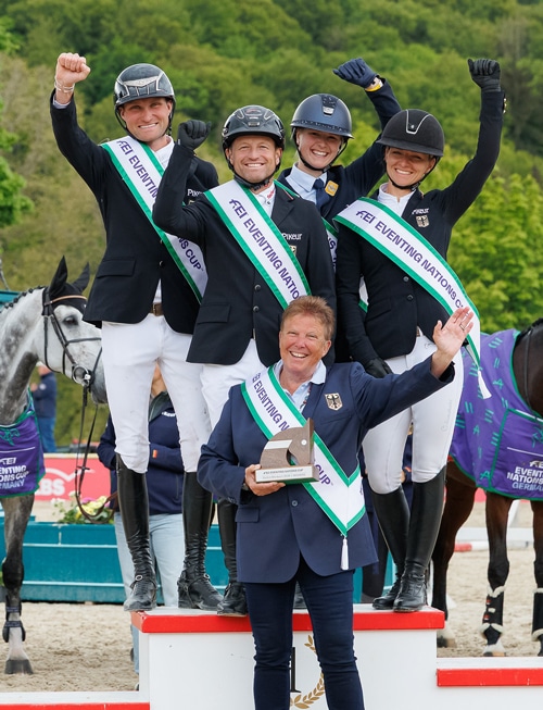 A team waving and smiling on a podium.