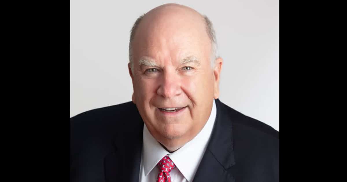 A smiling older gentleman in a suit.