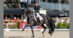 A man riding a black dressage horse in competition.