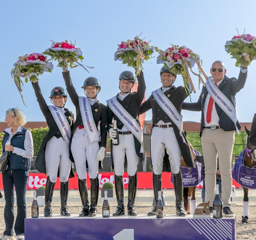 A smiling team waving from a podium.