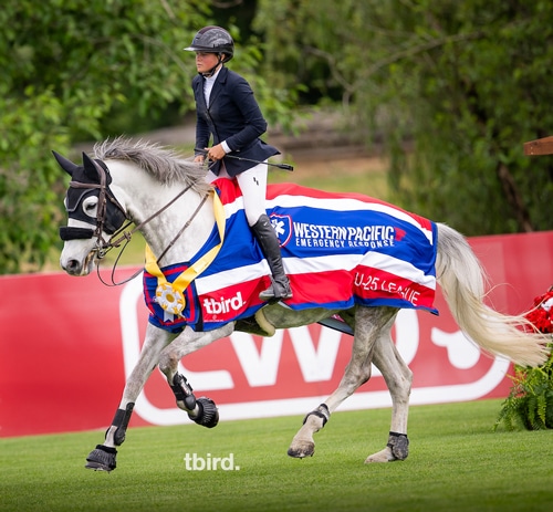 A woman riding a grey horse during a victory gallop.