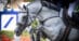 A grey horse in a severe bit jumping a fence.