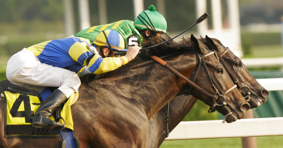Two horses racing at a track.