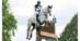 A woman jumping a grey horse over a cross-country fence.
