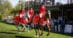 A team of riders wearing red jackets during a victory gallop.