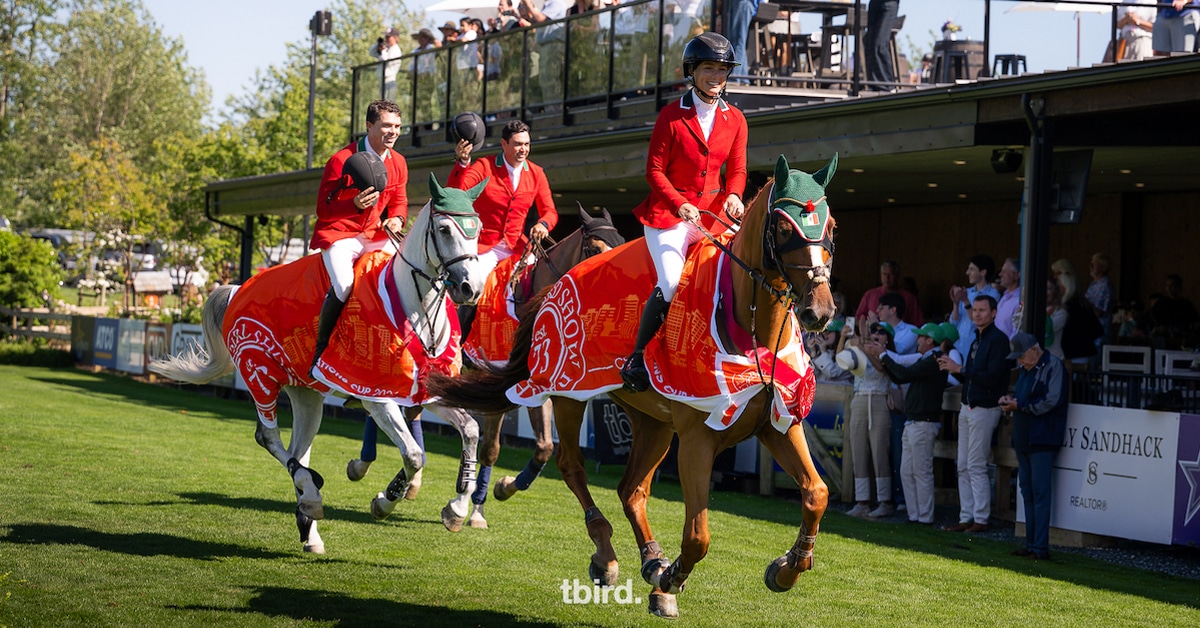 A team of riders wearing red jackets during a victory gallop.