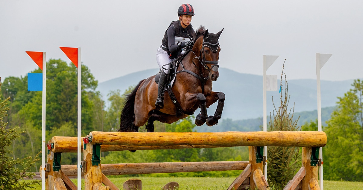 A woman jumping a bay horse over a cross-country fence at Bromont.