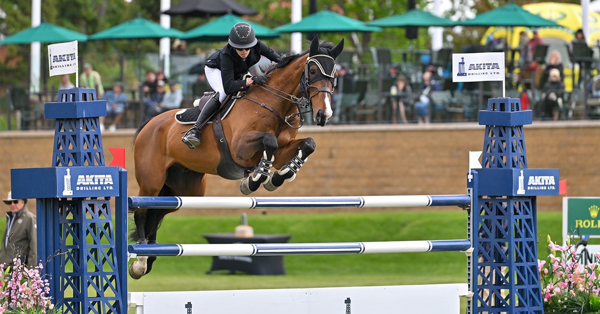 A woman jumping a bay horse over a fence at Spruce Meadows.
