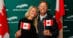 A smiling couple waving Canadian flags.