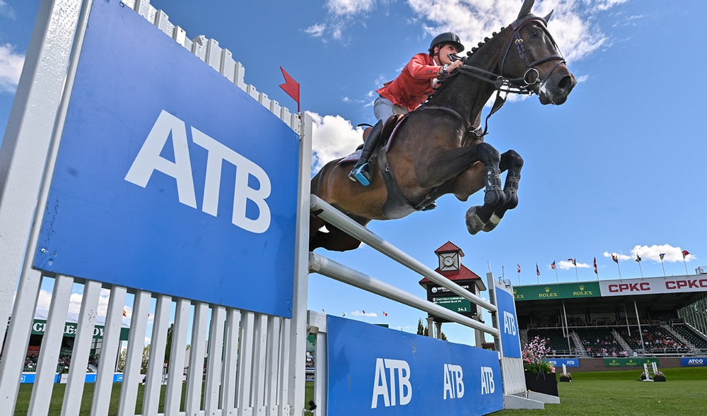 A man jumping a bay horse over a fence at Spruce Meadows.