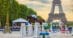 A man jumping a bay horse over a fence with the Eiffel Tower in the background.