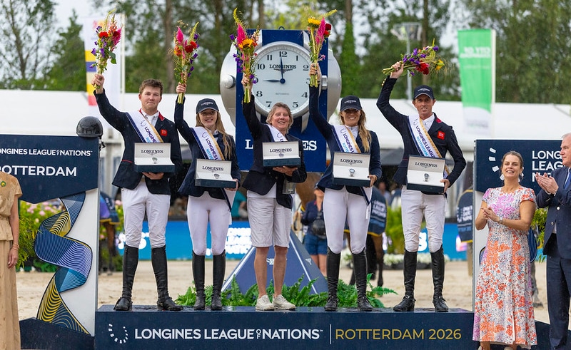 A team on a podium waving flowers.