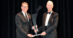 A man on a stage giving an award to another man.