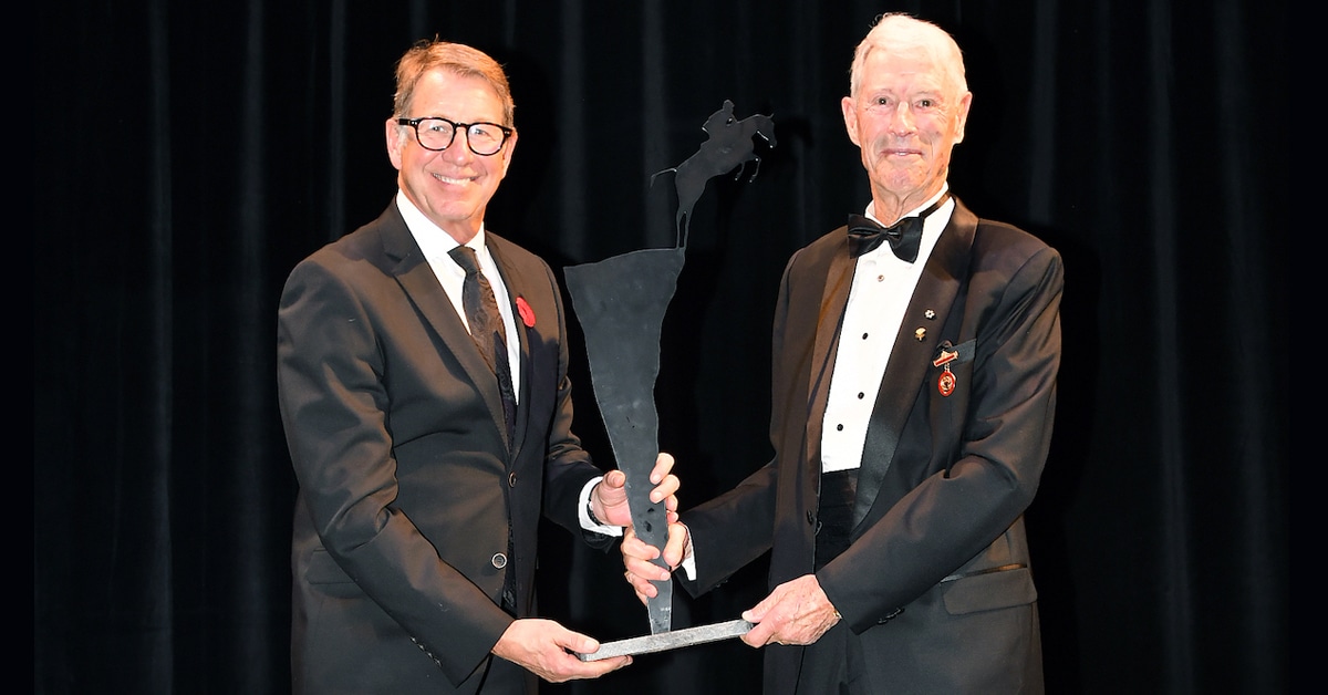 A man on a stage giving an award to another man.