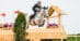 A young man jumping a grey horse over a cross-country fence.