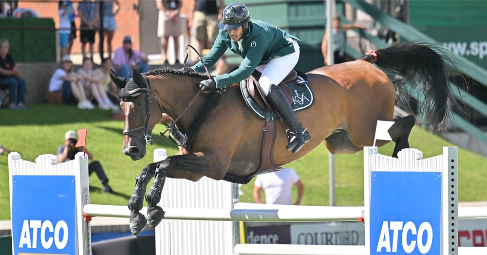 A man jumping a bay horse over a fence at Spruce Meadow.