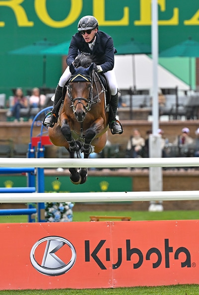 A man jumping a bay horse over a fence at Spruce Meadows.