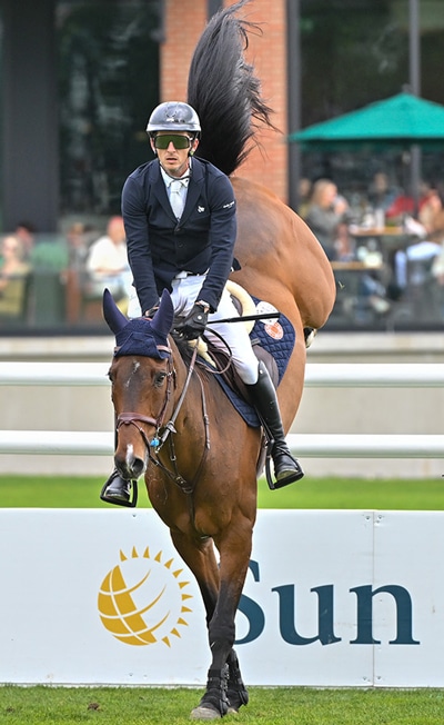 A man on a bay horse landing after a water jump.