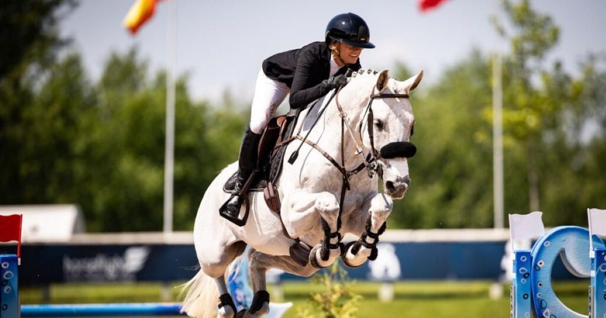 A woman jumping a grey horse over a fence at Traverse City.