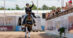 A smiling woman on a bay dressage horse, waving to the crowd.