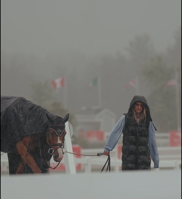 A woman walker her horse in fog and rain.