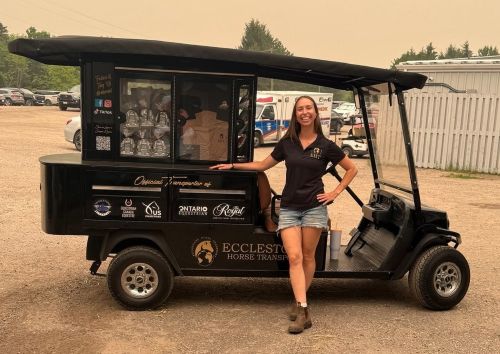 A woman standing beside a small truck.